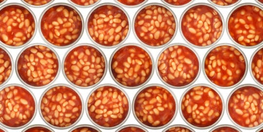Rows of opened cans filled with baked beans in tomato sauce, meticulously arranged and inspected with precision akin to X-ray Inspection Services, viewed from above. - Matrix Sciences